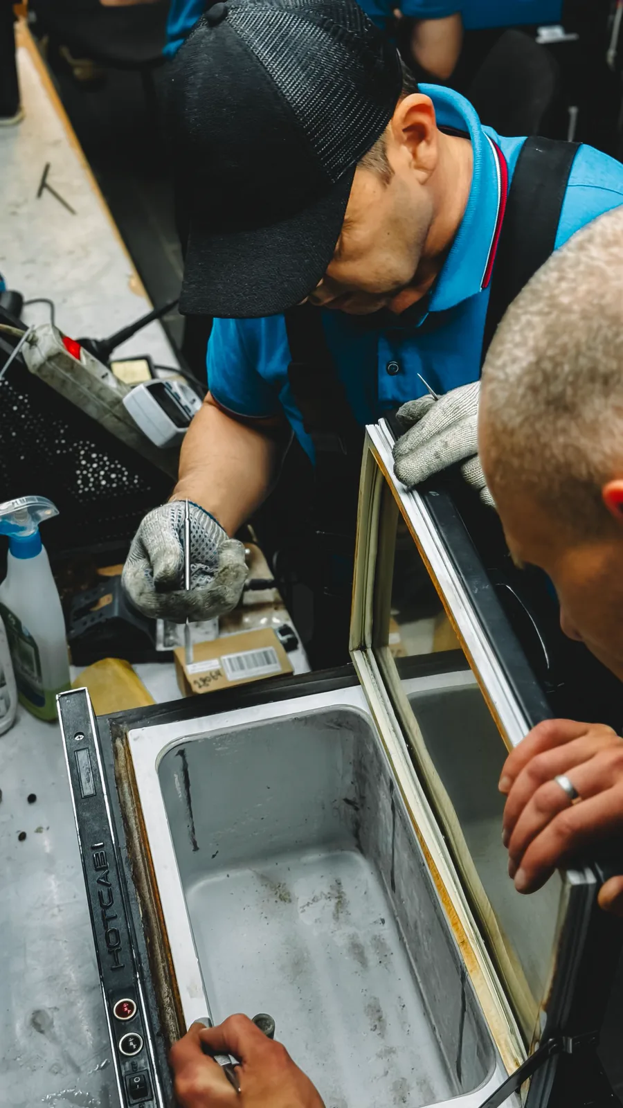 Dois técnicos trabalhando no sistema de refrigeração de um freezer
