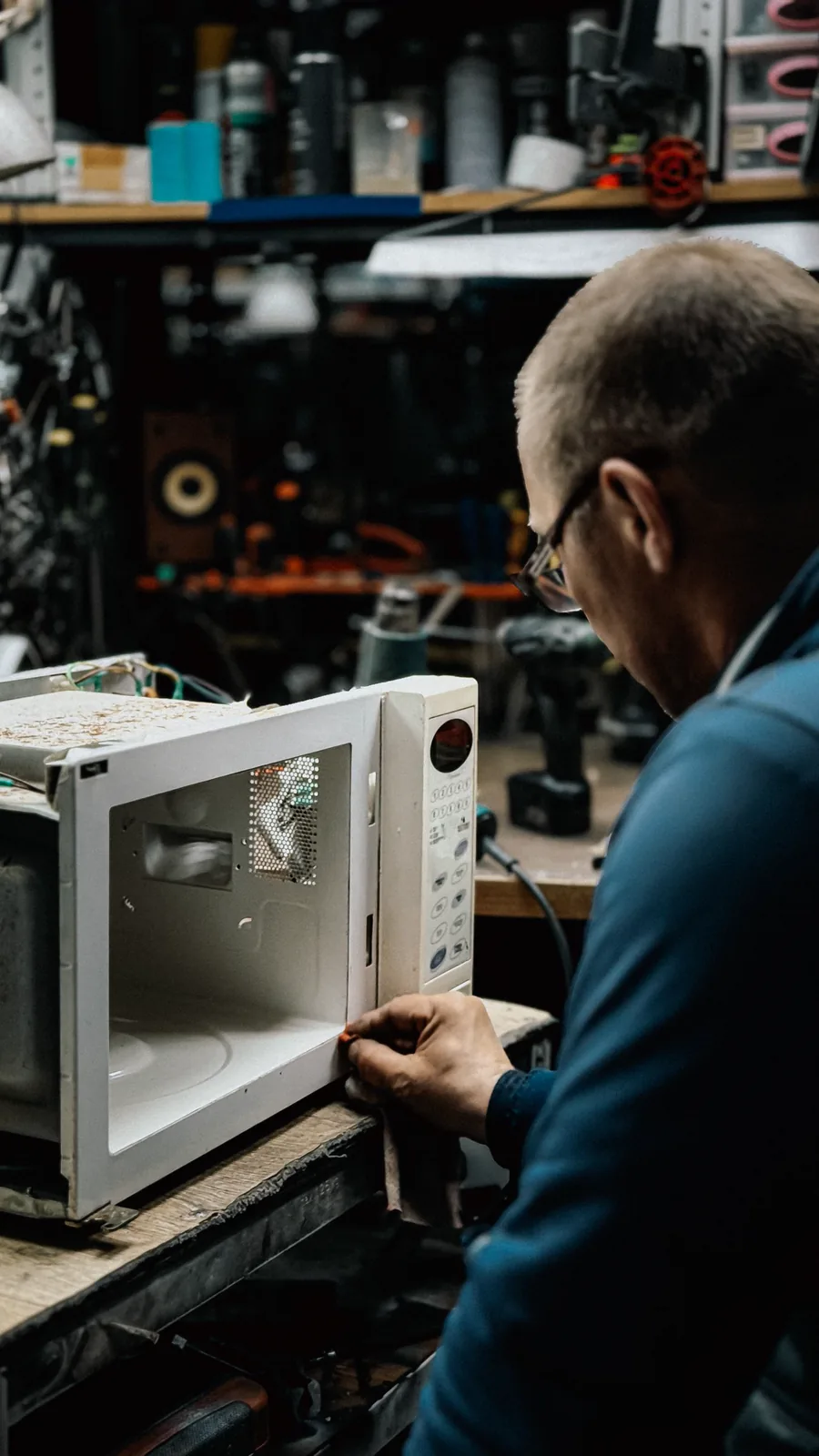 Técnico consertando o interior de um micro-ondas na bancada da oficina